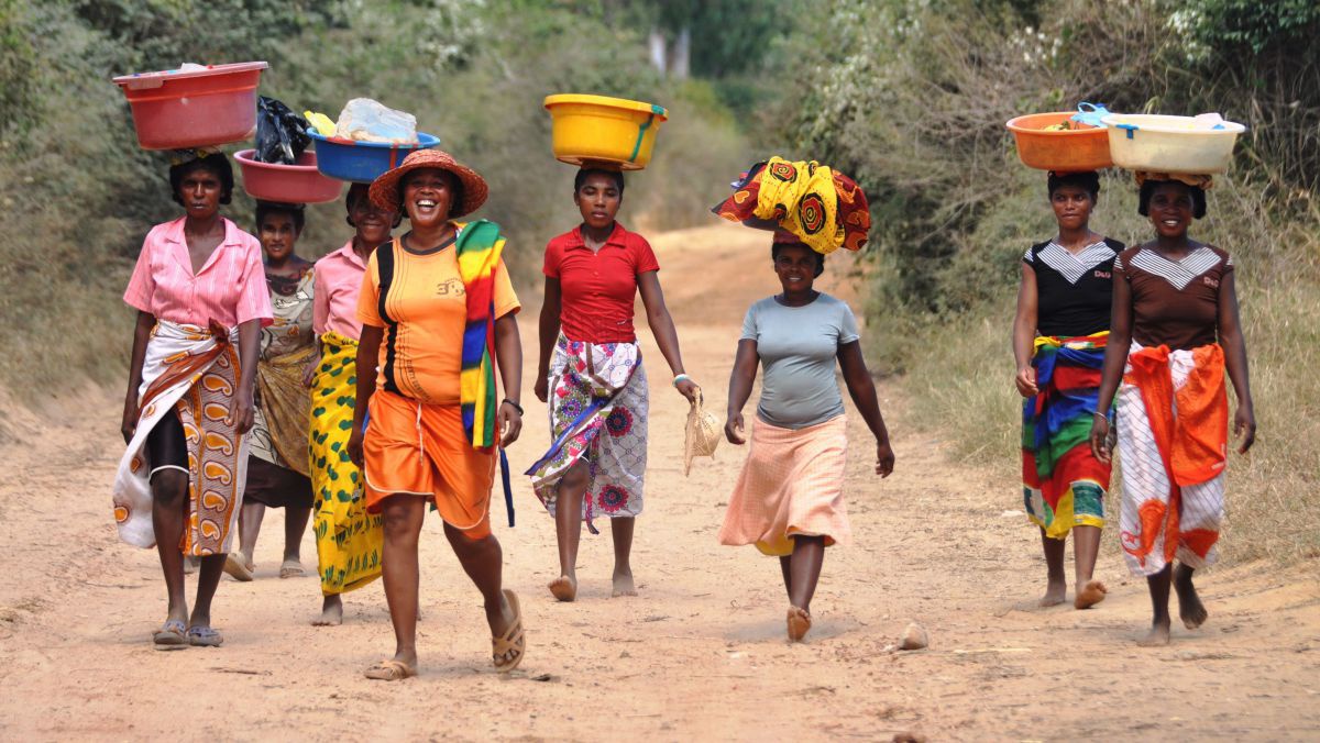 e afrikanische Frauen mit tragen Plastikkörbe mit Einkäufen am Kopf.
