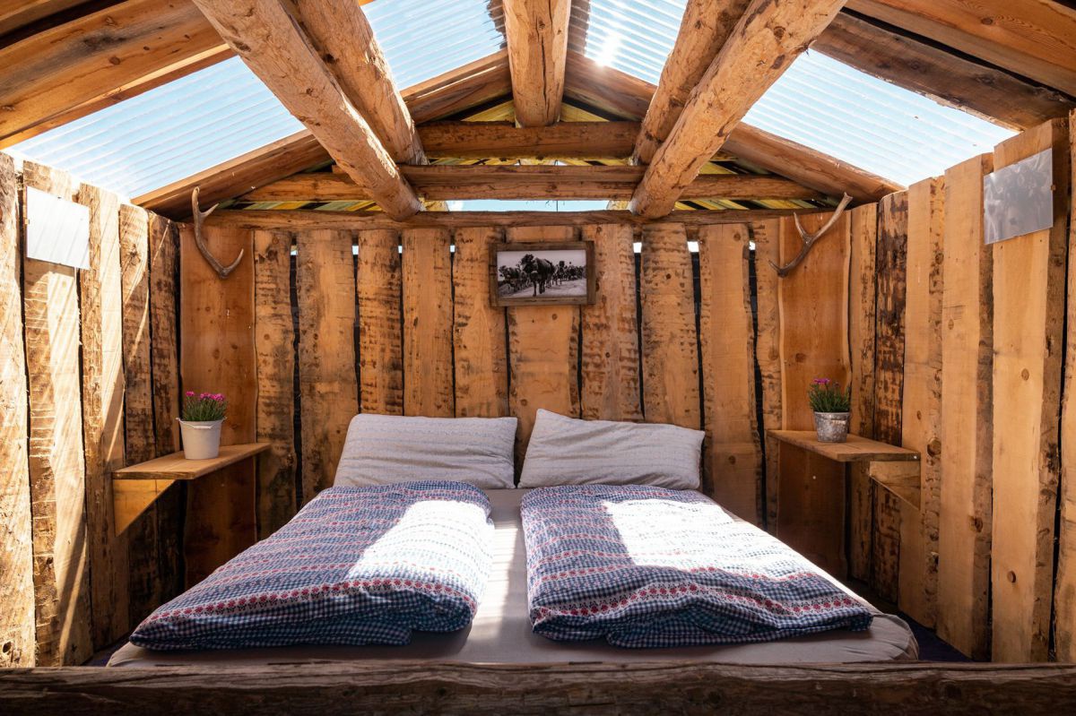 Doppelbett in Holzhütte mit Glasdach.