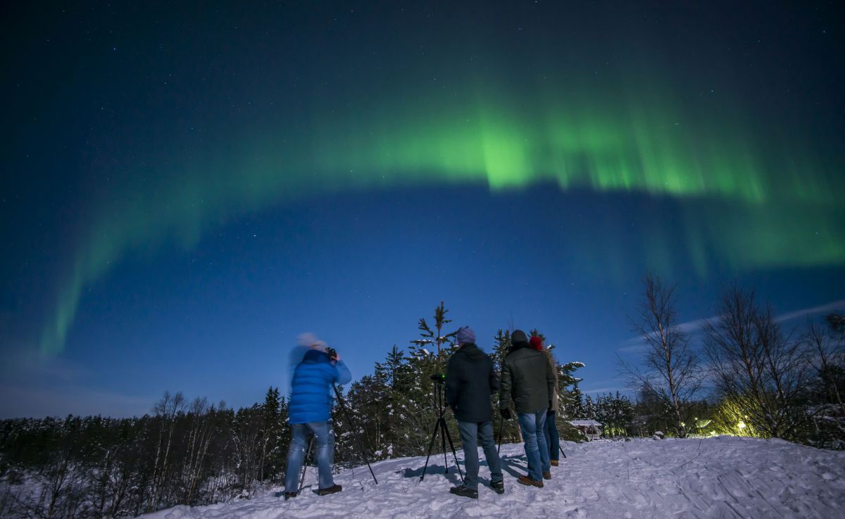 4 Personen beobachten grüne Solarlichter am Himmel
