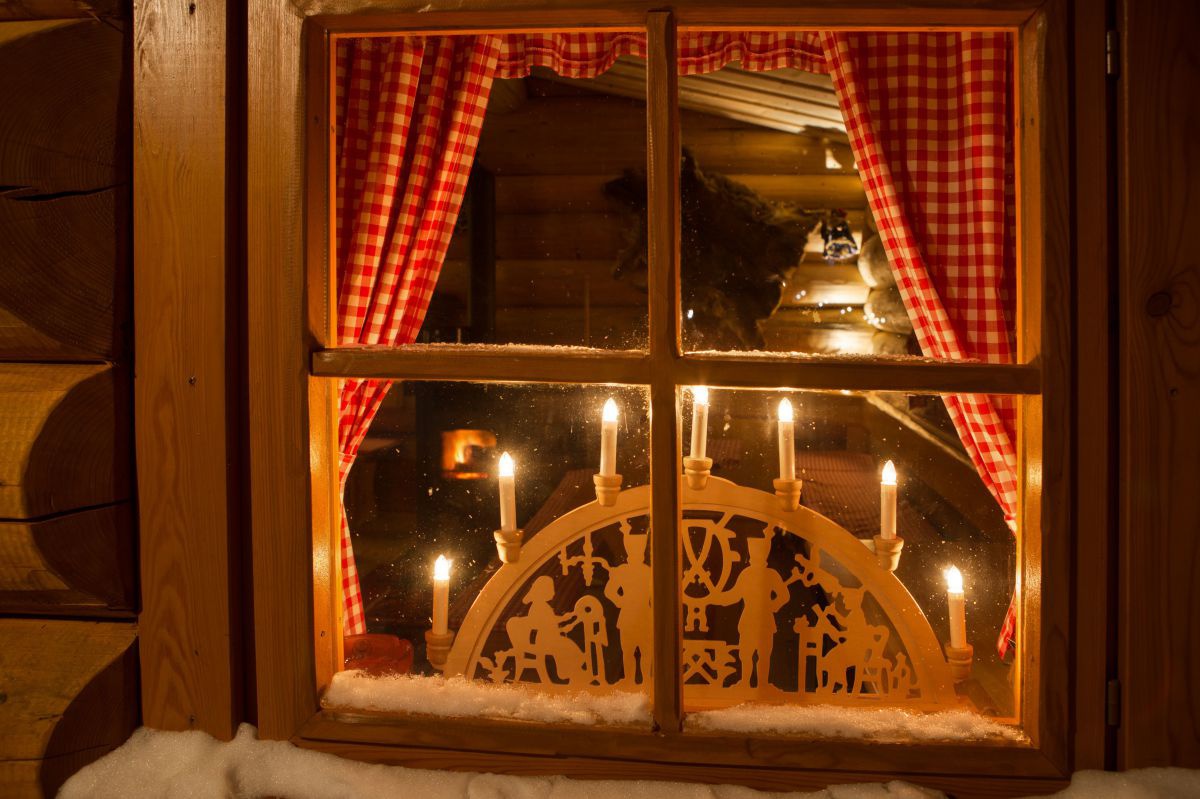 Beleuchteter, kunstvoll geschnitzter Holzbogen in einem Fenster.