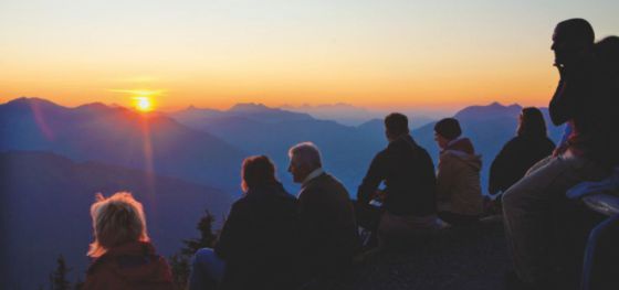 Gruppe von Wanderern mit Sonnenaufgang am Berg.