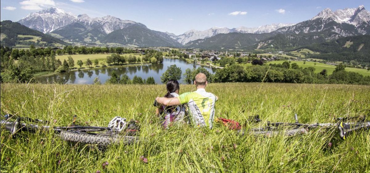 Zwei Mountainbiker machen eine Rast und blicken auf Saalfelden