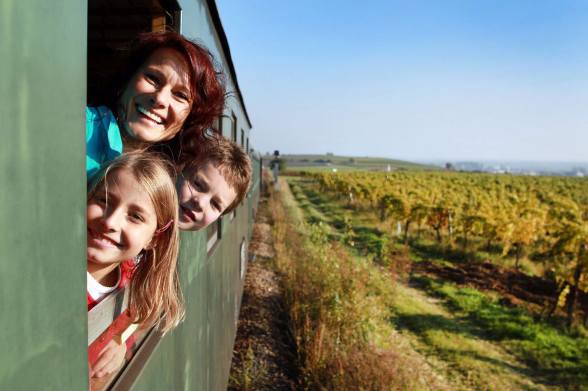 Frau und zwei Kinder schauen beim Fenster des Zuges raus.