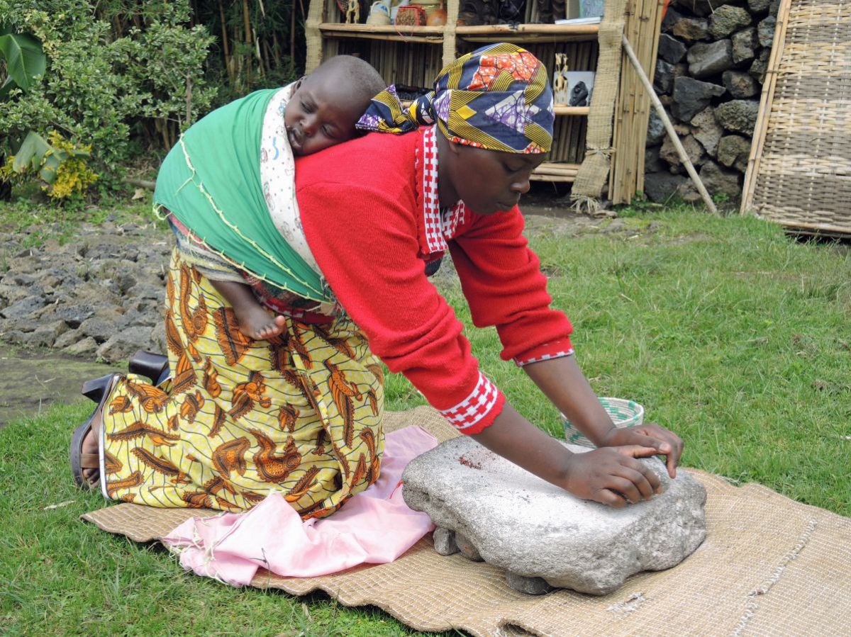 Frau mahlt Getreide auf einem Stein.