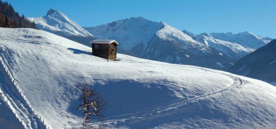 Bergpanorama und kleine Hütte in tief verschneiter Winterlanschaft