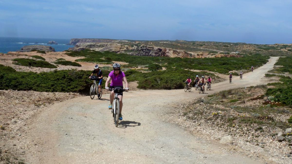 Gruppe von Radfahrern auf einer stubigen Küstenstraße.