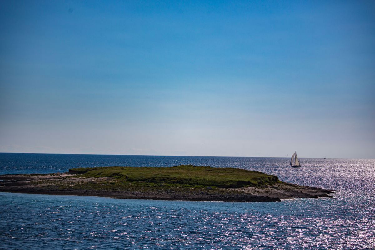 kleine Insel und Segelboot am Meer