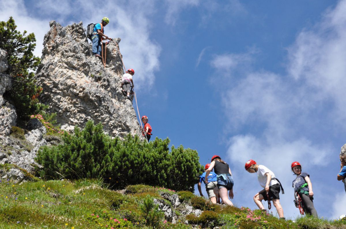 Kinder lernen an einem kleinen Felsen das Klettern