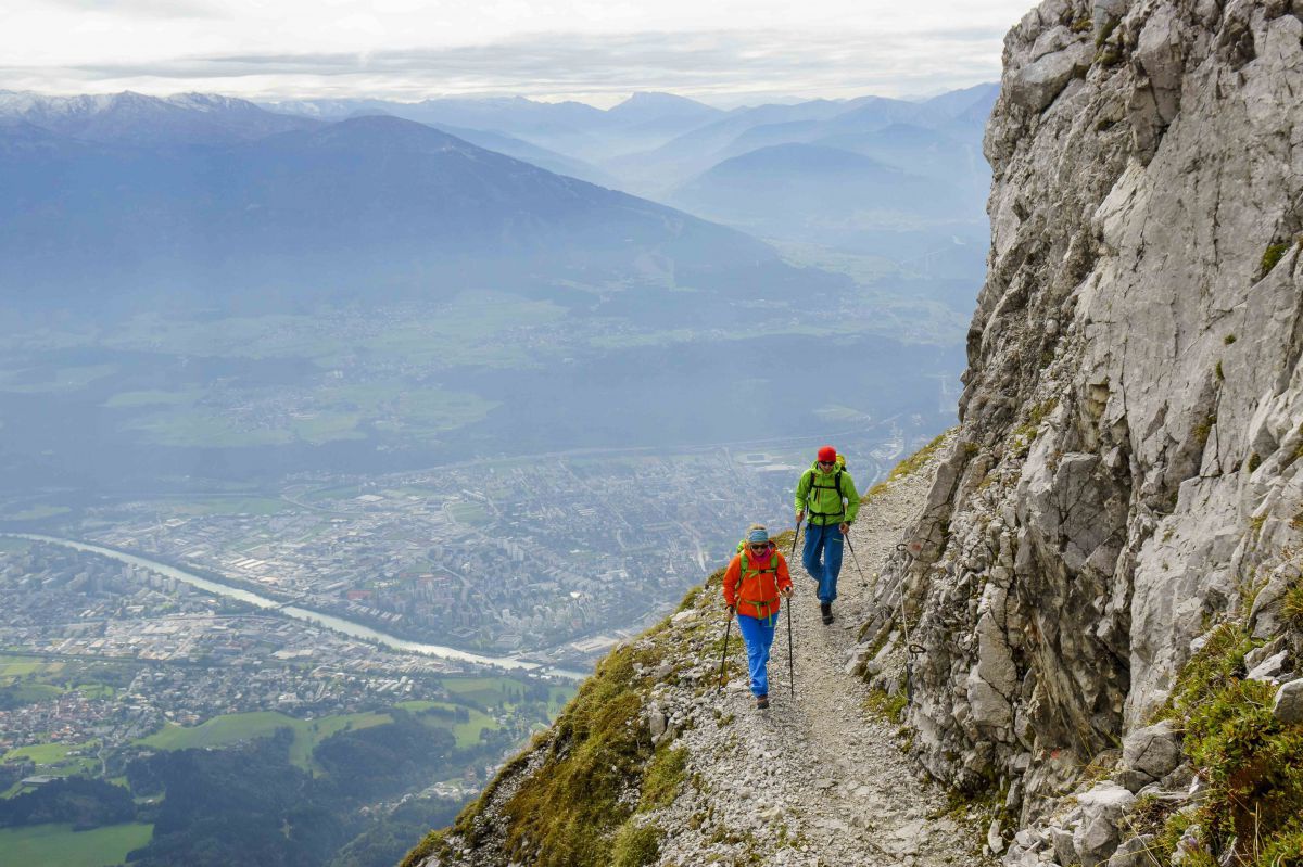2 Wanderer auf einem schmalen Steig hoch über Innsbruck.