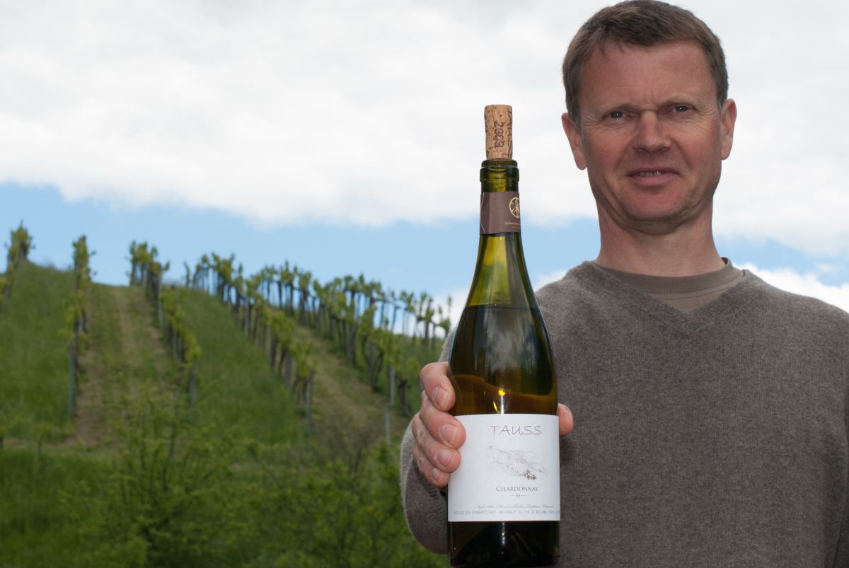 Winzer Roland Tauss mit einer Flasche seines biodynamischen Weines