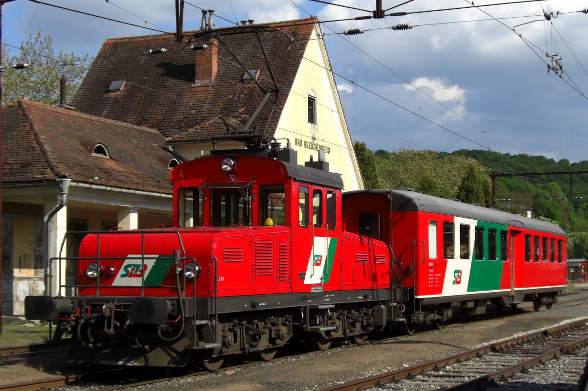 Rote Lokomotive mit einem rot-weiß-grünen Waggon im Bahnhof Bad Radkersburg.steiermaerkische_landesbahnen____gleichenbergbahn_e41-eb22-b-gl-4