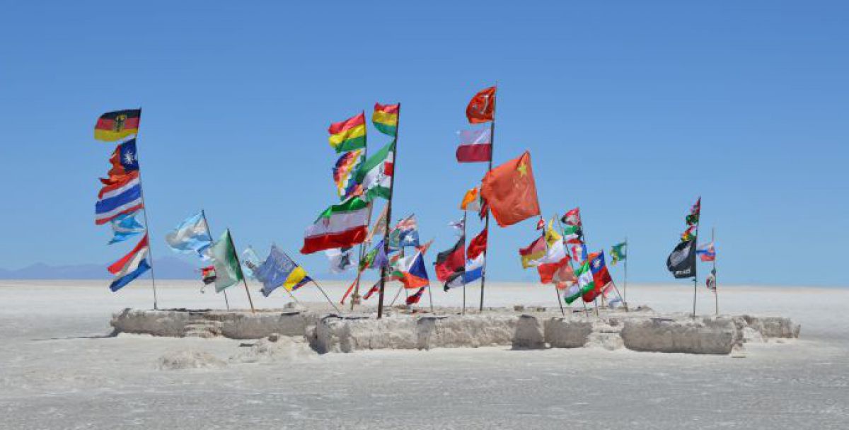 Viele unterschiedliche Landesflaggen stecken in Salzblöcken am Salzsee von Uyuni und wehen im Wind.