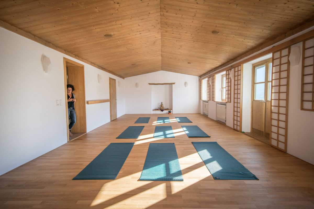 Leerer lichtdurchfluteter Raum mit Yogamatten am Boden.