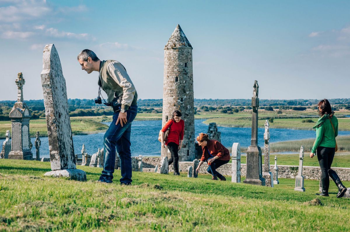 Touristen begutachten die Gräber bei Clonmacnoise.