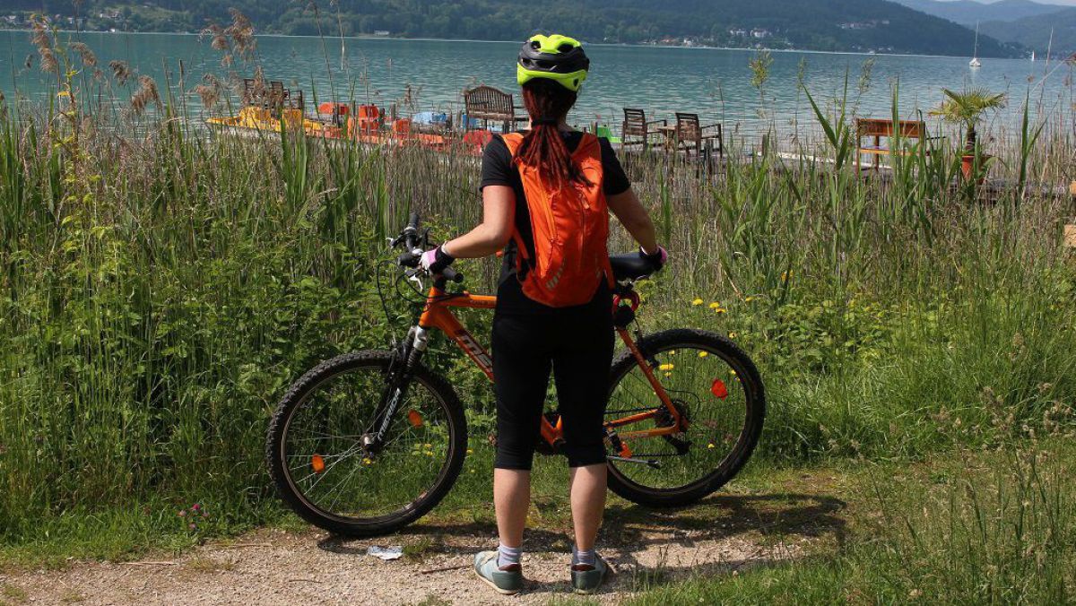 Frau stehend neben Fagrrad blickt audf den Worthersee.