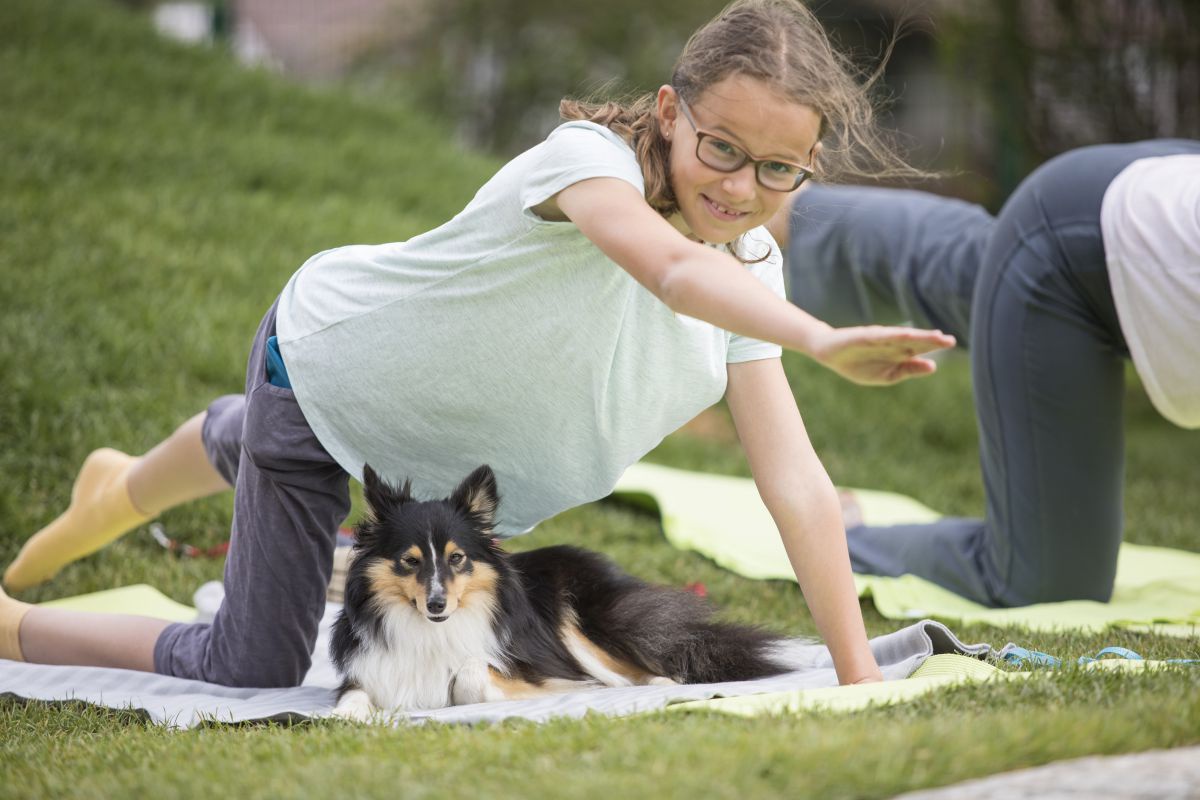 Kind mit Hund bei Yogaübung