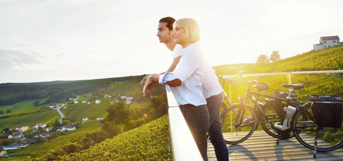 Mann und Frau auf einer Terrasse mit Blick übers Burgenland.