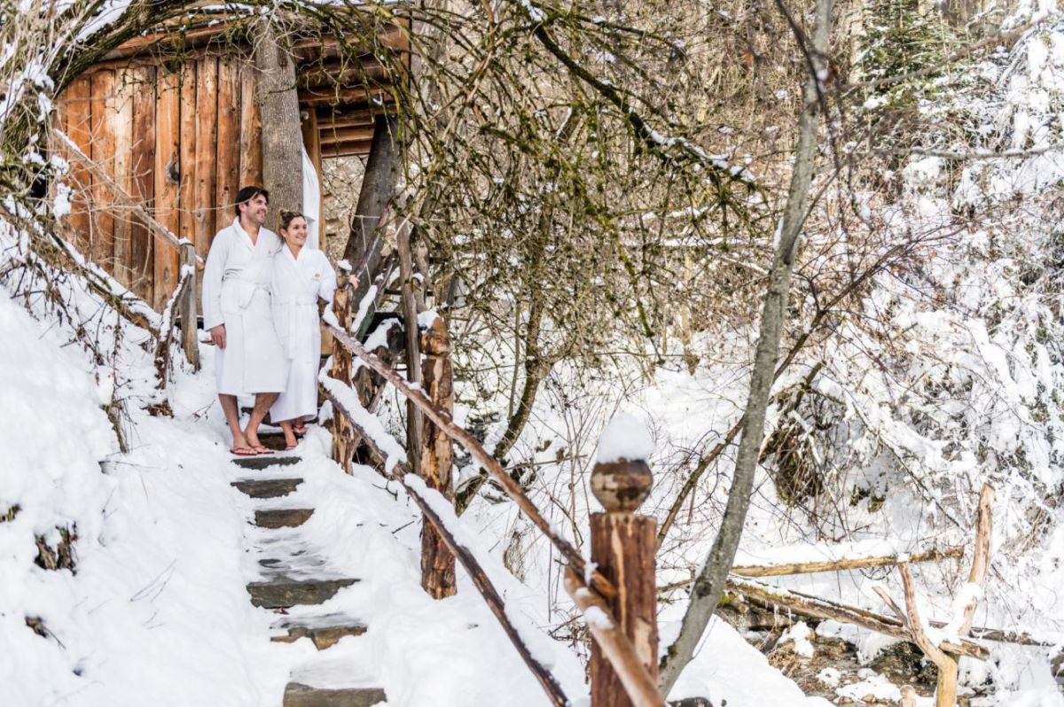 Paar im Bademantel am Saunapfad im Schnee.