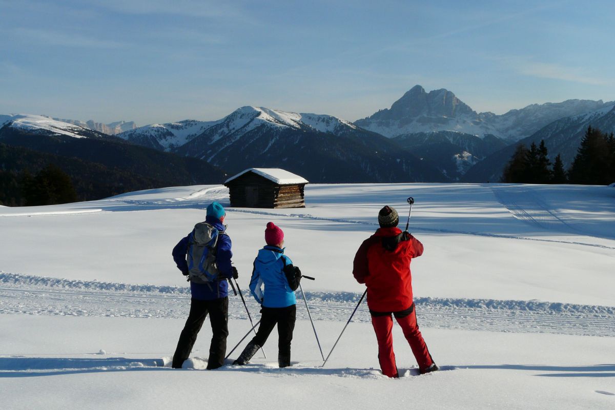 3 Personen wandern durch eine Winterlandschaft.