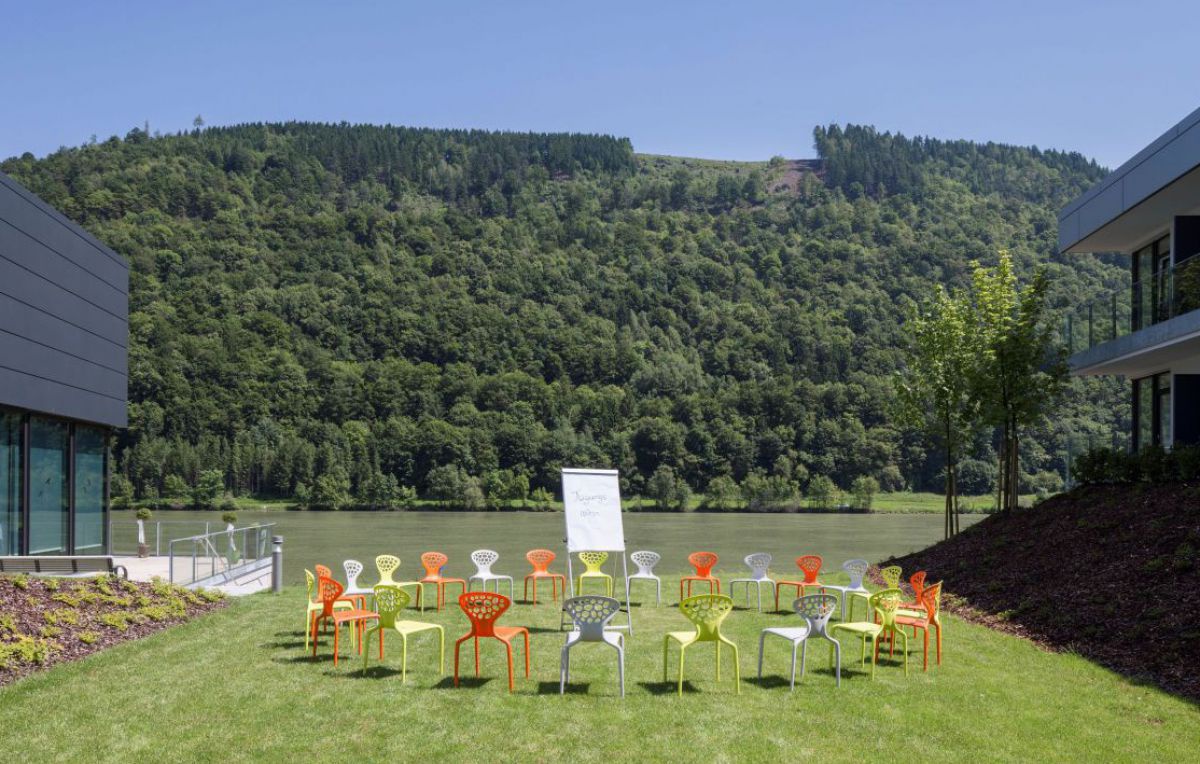 Sesselkreis rund um ein Flipchart auf einer Wiese mit Blick zur Donau.