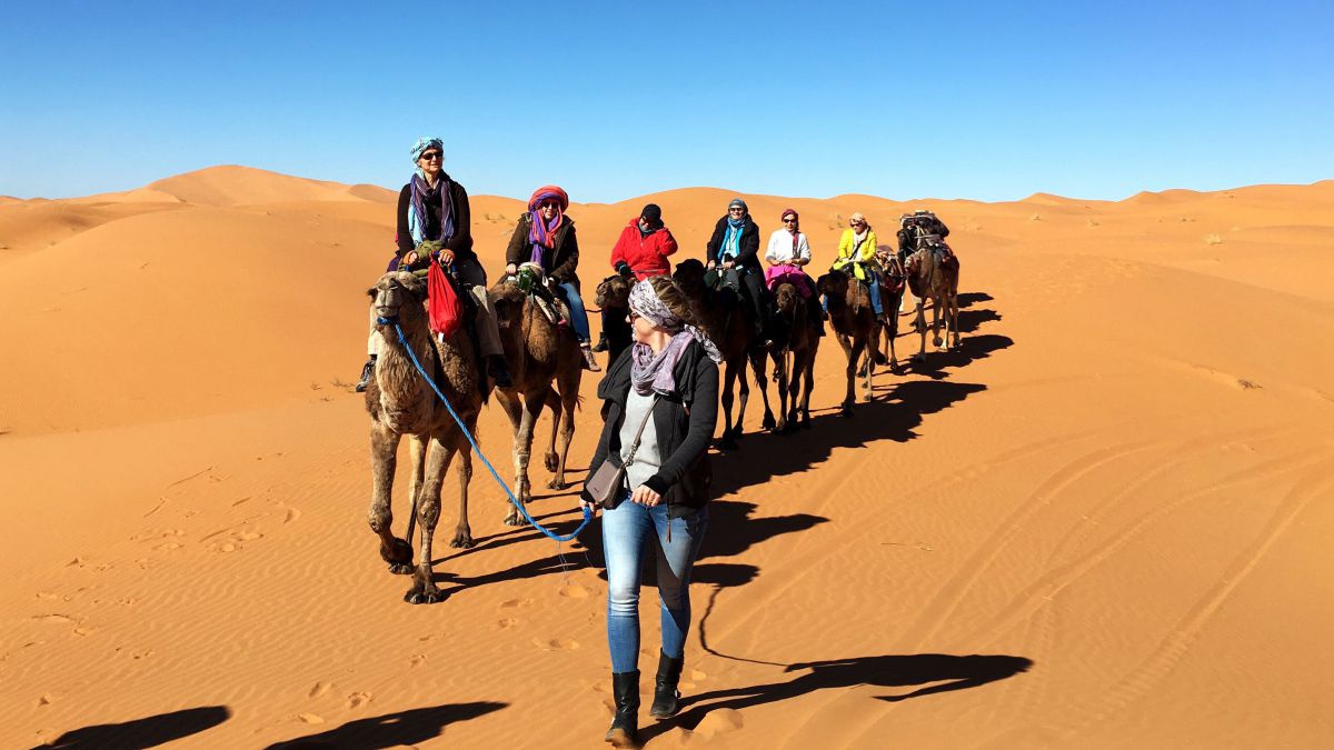 Karawane von 7 Frauen auf Kamelen in der Wüste