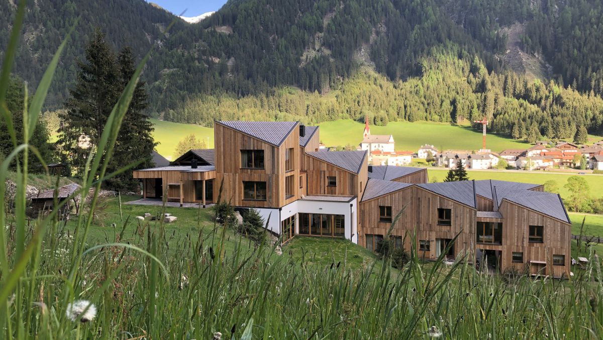 Blaslahof mit viel Holz von der Wiese oberhalb des Hauses aufgenommen.