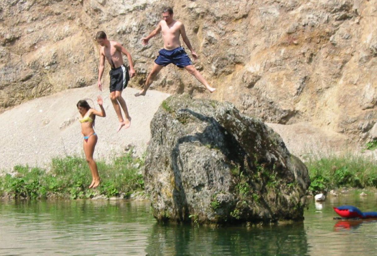 3 Kinder springen von einem Felsbrocken in die Ybbs.