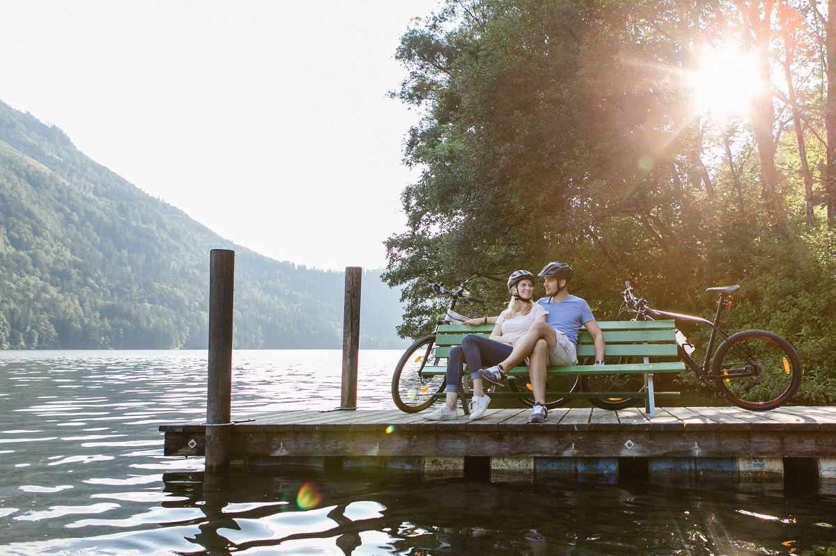 2 Radfahrer sitzen auf einer Bank an einem Steg am Lunzer See.