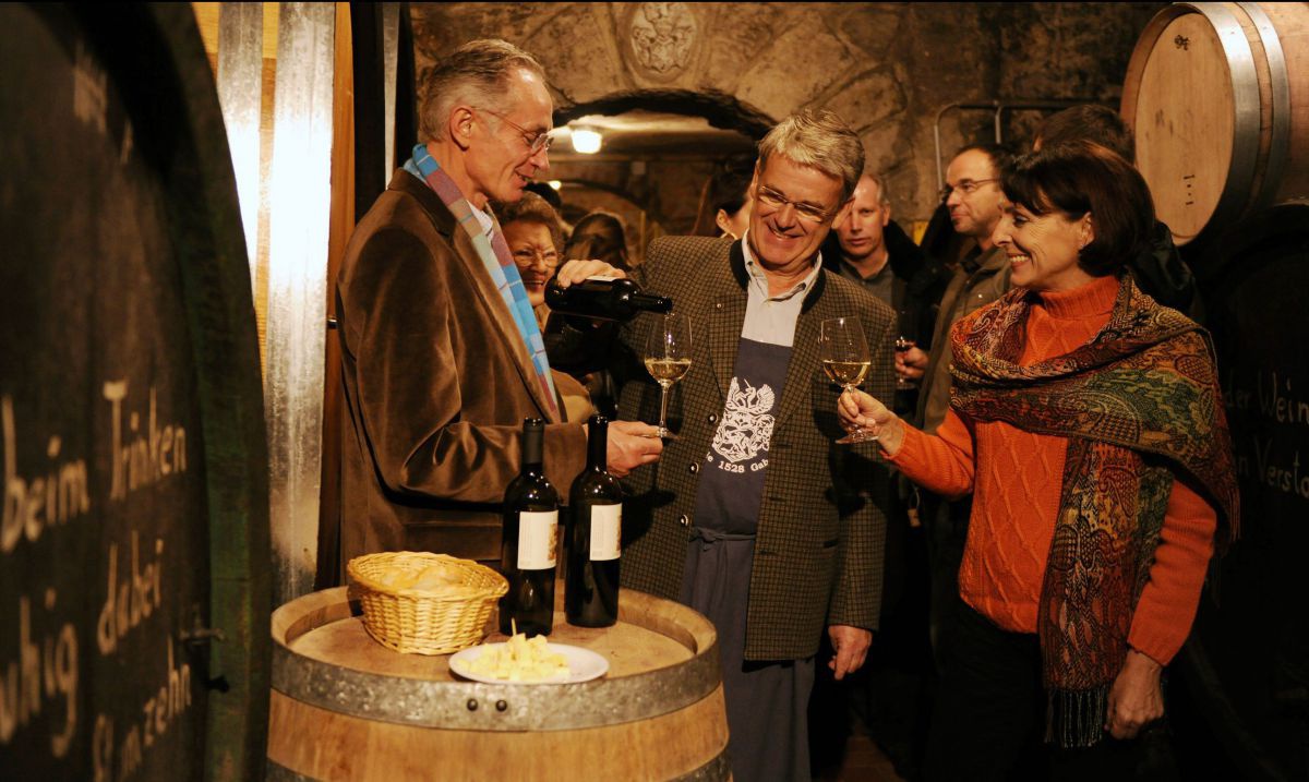 Winzer schenkt Gästen im Weinkeller Wein ein.