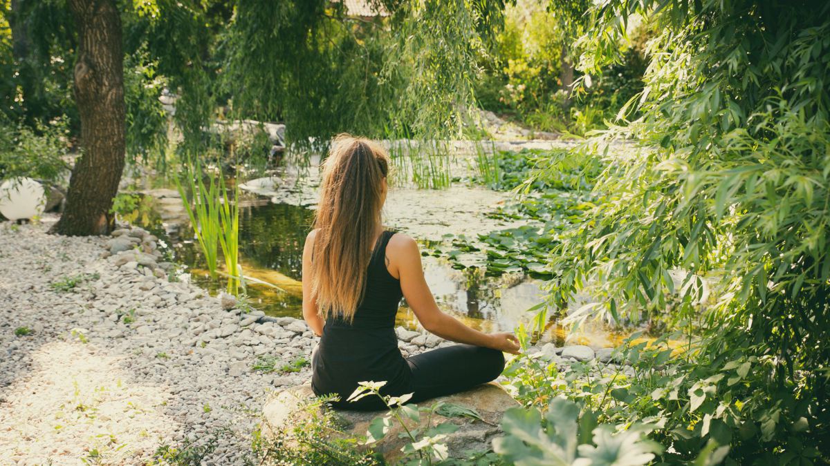 Frau nbeim Yoga im Garten.