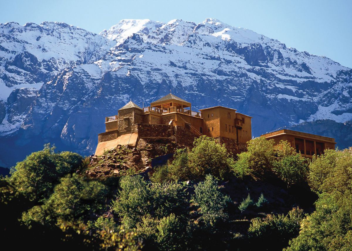 Hotel Kasbah du Toubkal, Anlage ais braunem Sandstein, dahinter ein mächtiger, schneebedeckter Berg.