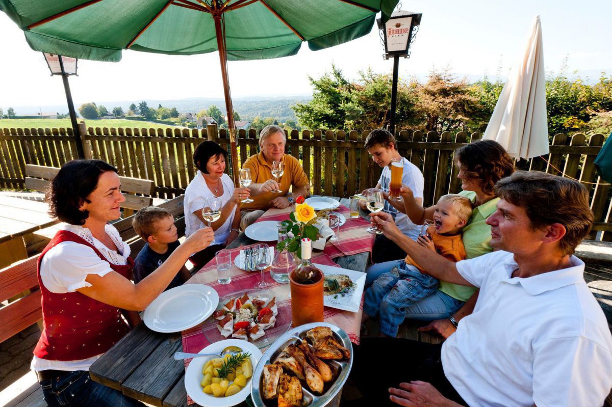 Menschen sitzen beim Essen auf der Terrasse.
