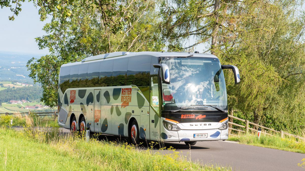 Terrer Reisebus fährt auf einer Lanstraße im Grünen.