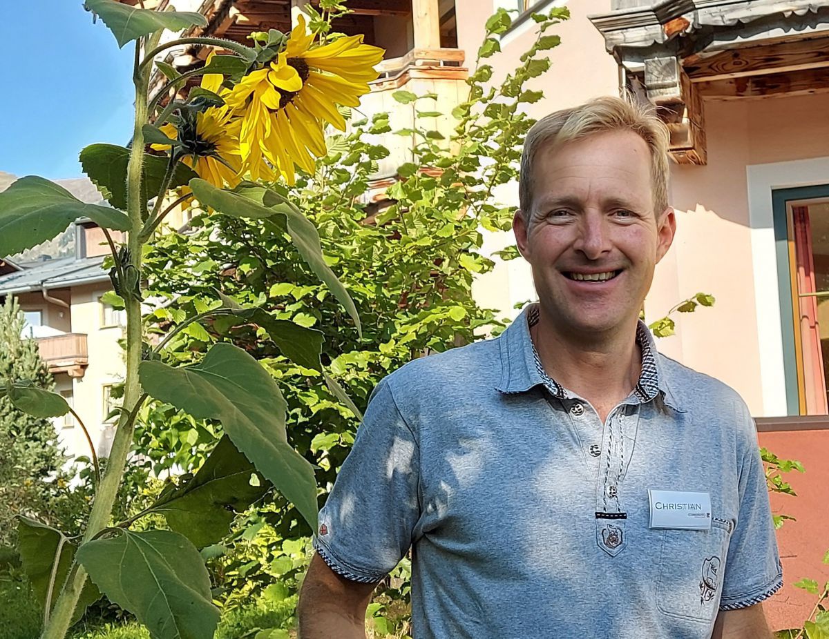 Christian Eder mit Sonnenblume vor seinem Hotel.