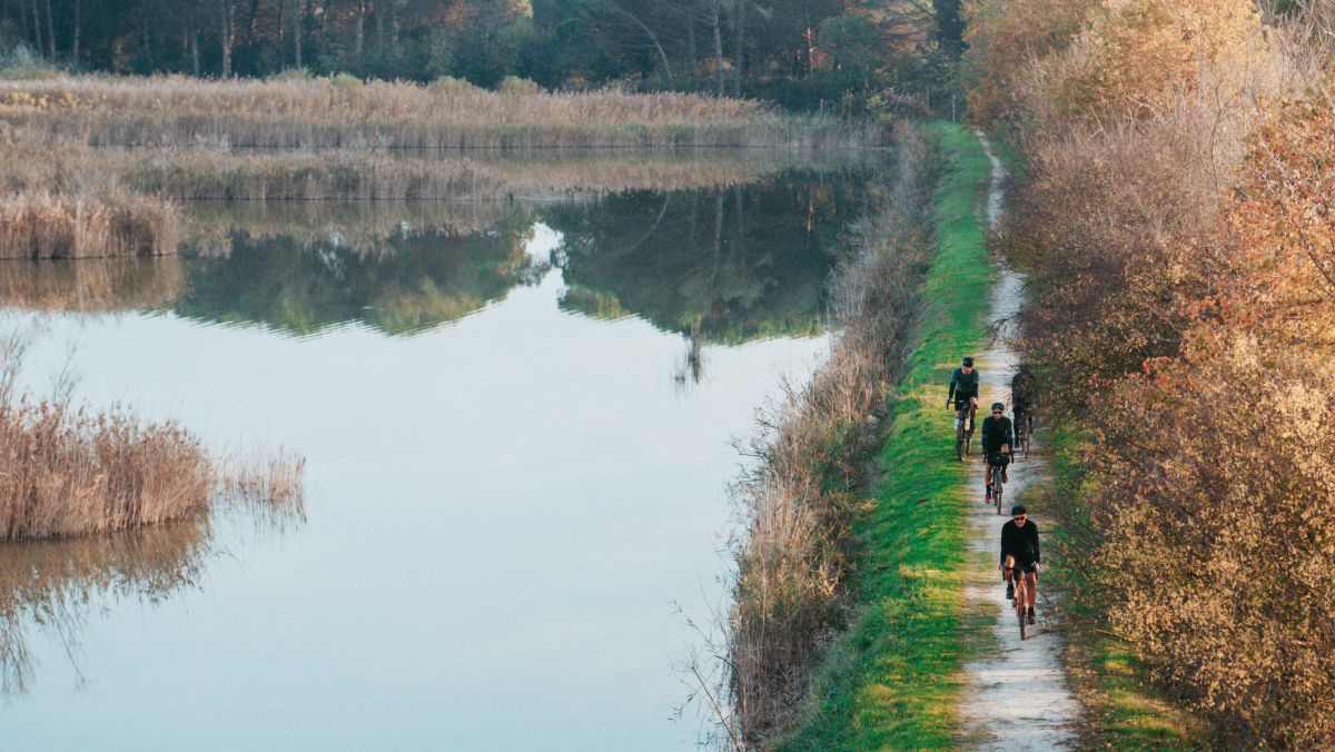 Drei Radfahrer auf einem Radweg auf einem Damm zwischen Meer und Land.