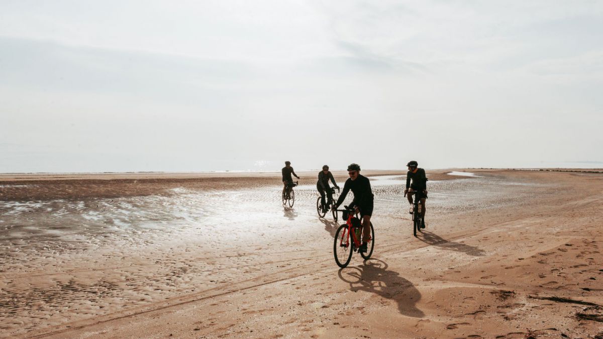 4 Radfahrer am Sandstrand.