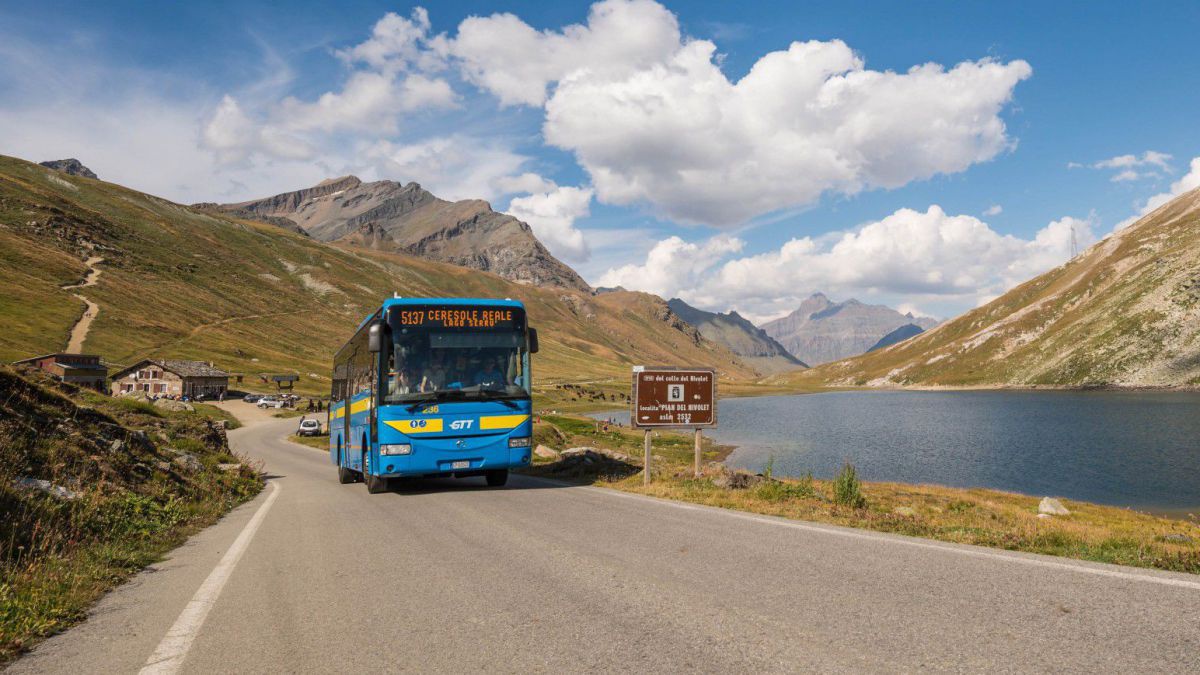 Blauer Bus auf der Passhöhe neben einem Gebirgssee.