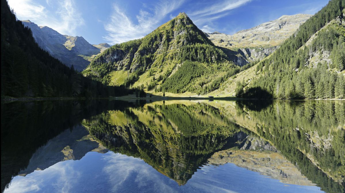 Gebirgssee. Im Wasser spiegelt sich der Berg.