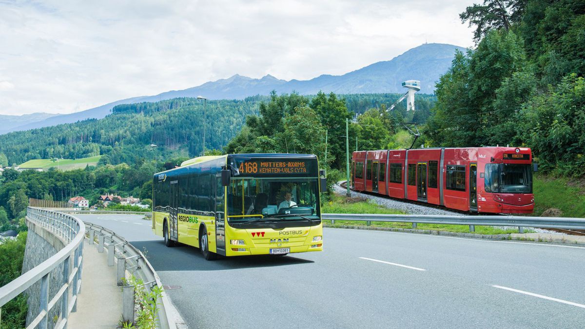 Delber Bus auf der Straße fährt neben ritem Zug auf der Schiene.