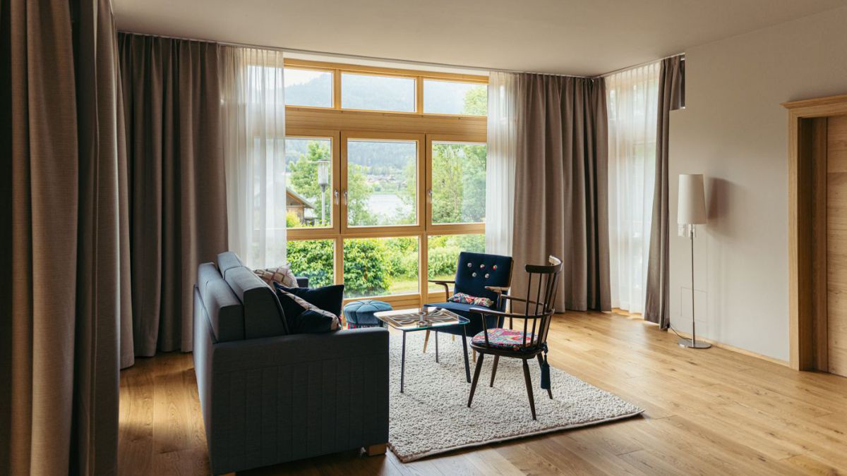 Wohnraum im Appartmenthotel: Couch, Toisch, 2 Sessel, Blick auf den See.