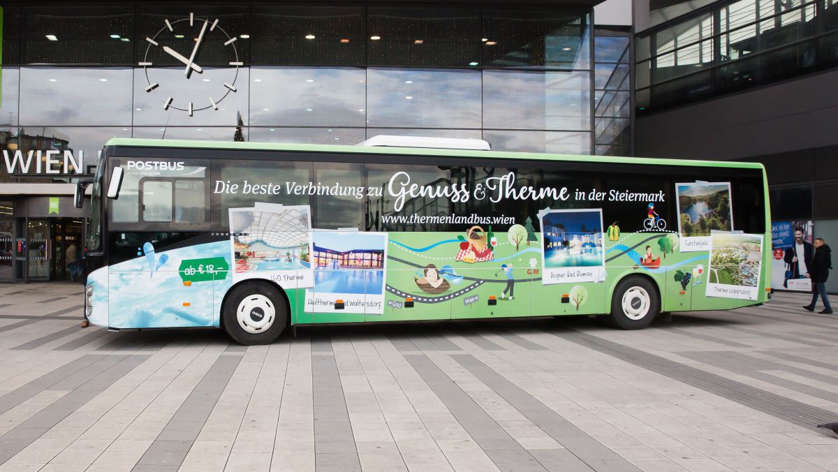 Grün bemalter Bus mit Bildern der einzelnen Thermen vor dem Wiener Hauptbahnhof.