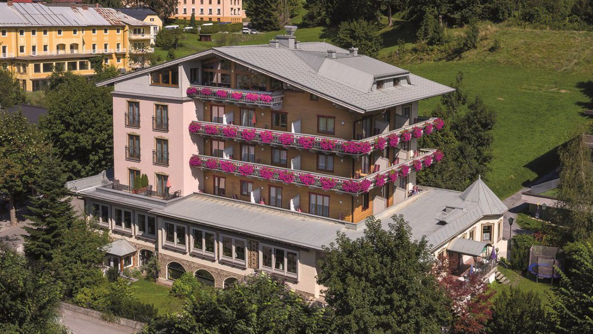 Ausssenansicht vom Völserhof. mehrstöckiges Haus mit Balkonen rundherum. Dort blühen lila Blumen.