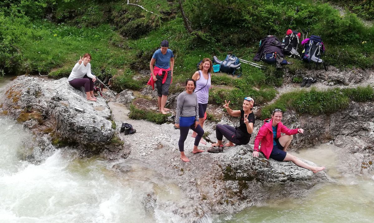 Gruppe von 6 Frauen sitzt auf Felsen am Ufer des Grimmingbaches. 