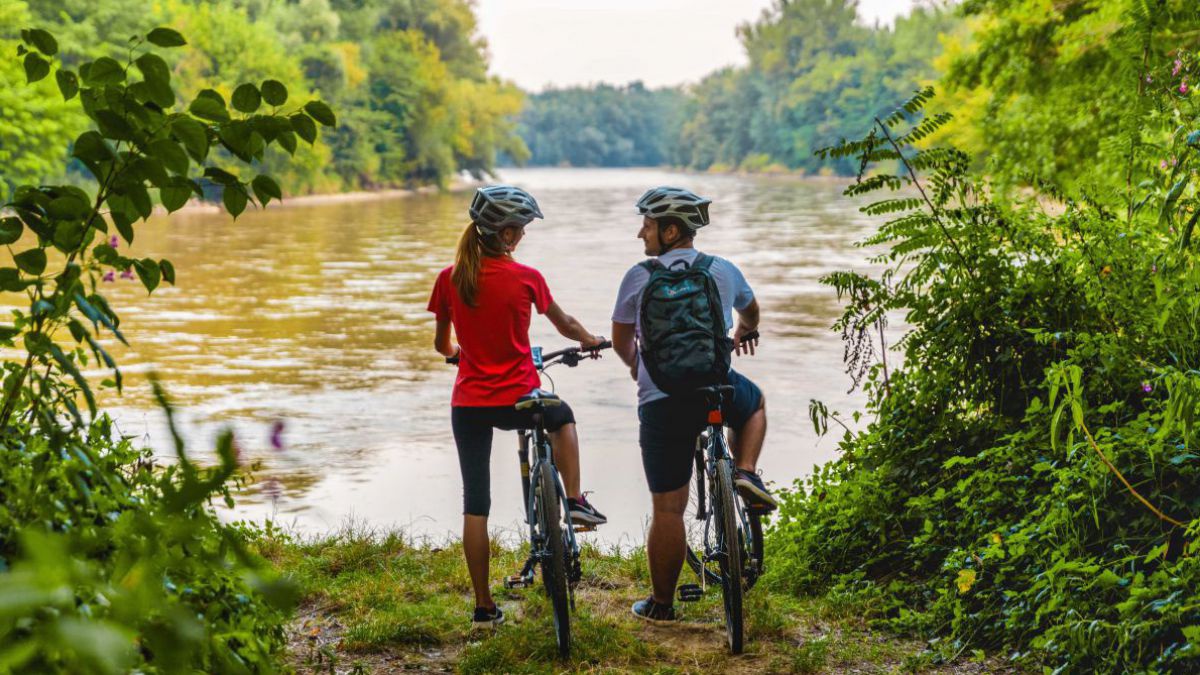Zwei Radfehrer*innen stehen an einem Fluss.