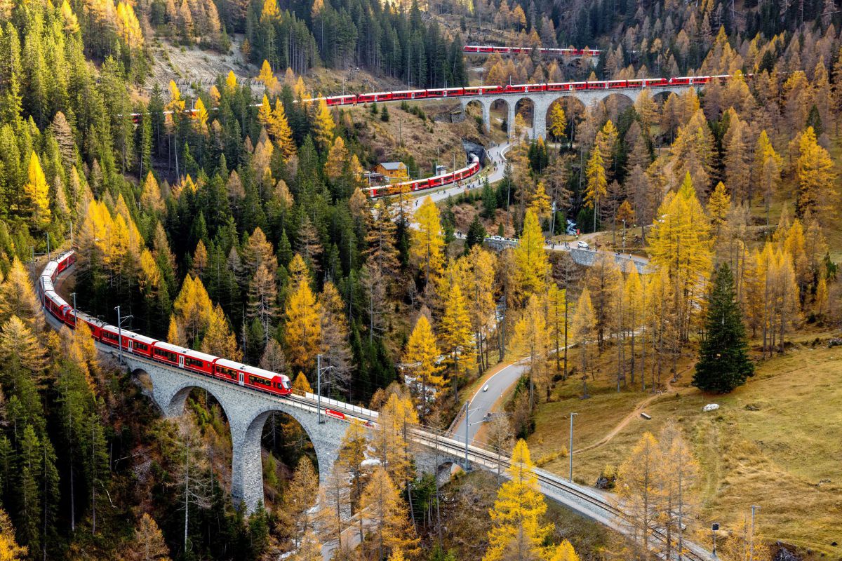 Roter Zug schlängelt sich über Viadukte talwärts.