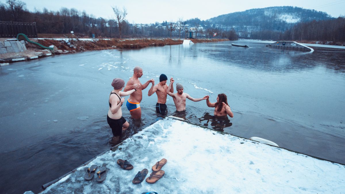 5 Personen steigen in Badekleidung in das eiskalte Wasser.