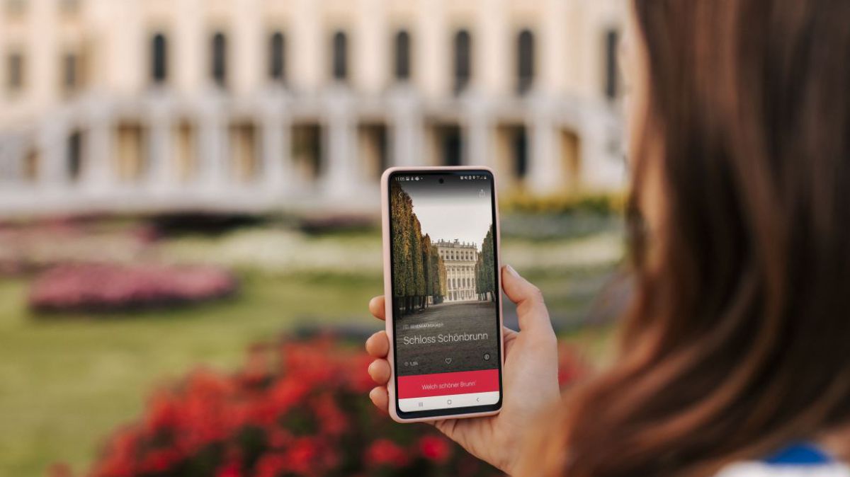 Eine Frau ist in Schönbrunn unterwegs und erhält über eine App auf ihrem Smartphone Infos über die Sehenswürdigkeiten.