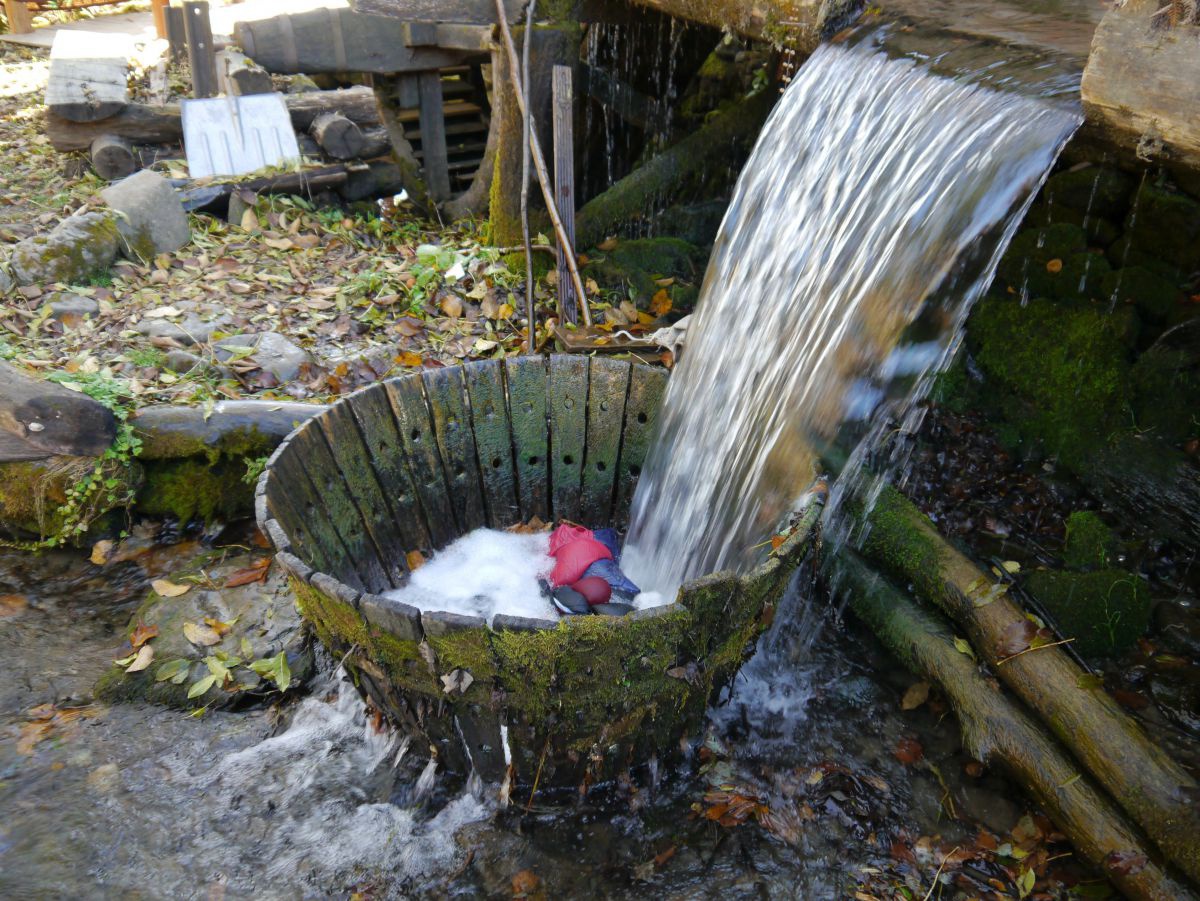Wasser fließt inn einen Holzbottich mit Wäsche.