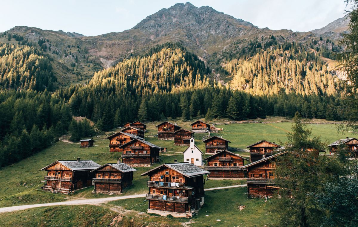 Holzhäuser und eine Kapelle eingebettet in die Berglandschaft.