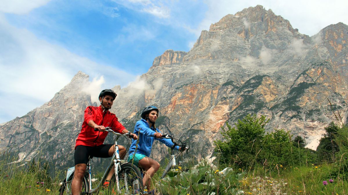 Ein Radfahrerpaar unterwegs am Fuße hoher Berge.